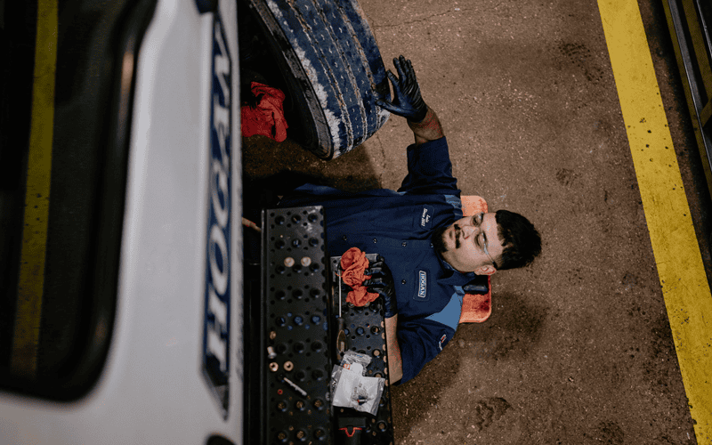 A Hogan technician working underneath a truck.