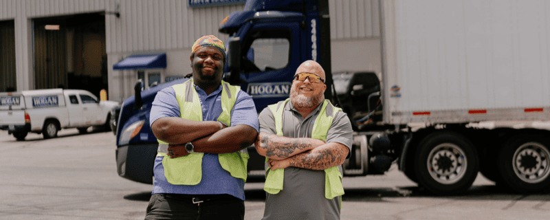 Two Hogan drivers in front of a Hogan truck.