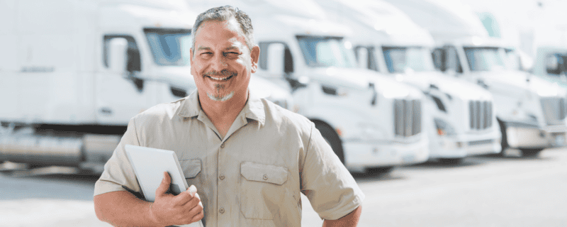 A supervisor in front of a line of white trucks.